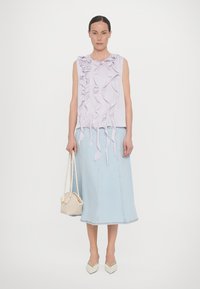 Light purple sleeveless top with ruffled design, paired with a light blue denim midi skirt and a small woven bag. Neutral pointy-toed shoes.