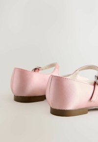 Ružové saténové baletné baleríny majú hladký povrch, zaoblenú špičku a ozdobný remienok s kovovou sponou. Podrážka je hnedá a plochá.