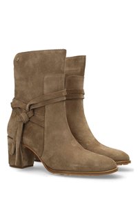 Bottes ankle en suede marron avec un talon carré, présentant un détail de lien noué, une texture lisse et un design légèrement pointu.