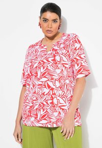 Top de manga corta con un diseño en V, de colores rojo y blanco, que presenta motivos florales abstractos sobre una tela ligera.