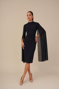 Mørkeblå midi kjole med figursydd overdelt, høy hals og gjennomsiktige kappe-ermer. Glatt stoff, minimal detaljering, paret med nude hæler.