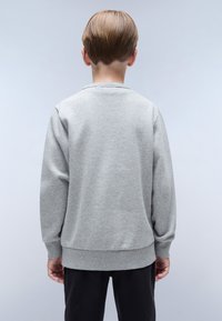 Sudadera gris con puños y dobladillo acanalados, diseño básico de cuello redondo, fabricada con material suave, mostrada desde la parte posterior.