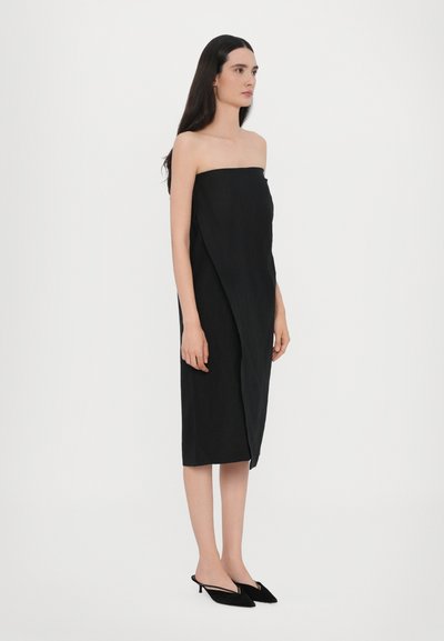 Sorte, stroppeløs, kjole i midten med draperte detaljer. Laget av glatt stoff, med en asymmetrisk snitt og minimal pynt.