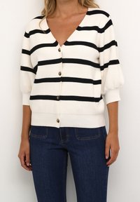 Czarny i biały kardigan w paski z głębokim dekoltem w kształcie V, krótkimi bufkami i złotymi guzikami z przodu, wykonany z miękkiego, teksturowanego materiału.