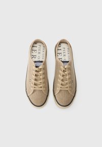 Beige kanvas sneakers med runde tær, snørelåsdesign og kontrasterende mørkeblå gummisåle. Innvendig fôr har trykt logo-tekst.