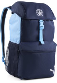 Zaino blu navy con dettagli azzurri, dotato di tasca laterale in rete, tasca anteriore con zip e logo del Manchester City sul cappuccio.