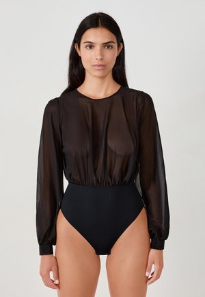 Schwarzer Body mit transparenten langen Ärmeln, Rundhalsausschnitt und elastischem Bund, kombiniert mit einem hochgeschnittenen Unterteil. Glatte Textur, figurschmeichelndes Design.