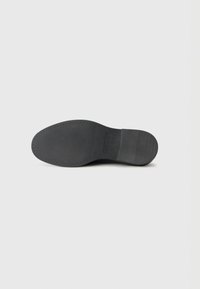 Black shoe sole, rubber material, rounded shape, textured surface, smooth edges, with light ridging at the heel and flat front.