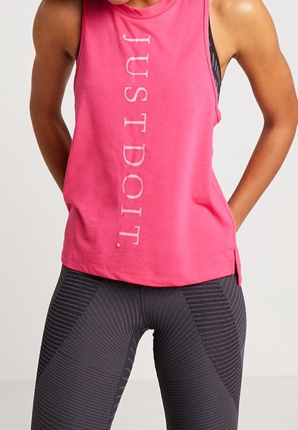 Rosa ärmlös linne med texten "JUST DO IT." i vitt, kombinerad med svarta leggings med ett mönster av texturerade ränder.