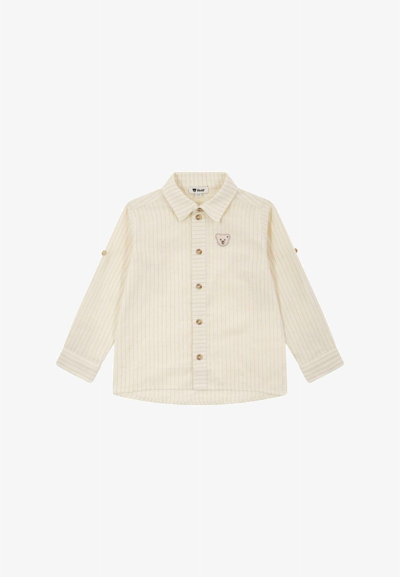 Crème-kleurige langärmelige shirt met verticale strepen, knoopsluiting en een kleine berenpatch op de borst. Zachte, gestructureerde stof.