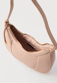 Ροζ δερμάτινη τσάντα ώμου με χρυστό φερμουάρ μερικώς ανοιχτό, που αποκαλύπτει μαλακή εσωτερική επένδυση και μικρή εσωτερική τσέπη με ετικέτα μάρκας.