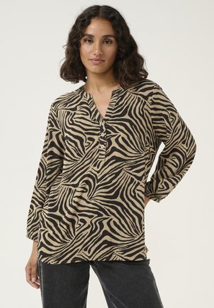 Chemise beige avec un motif de rayures noires de zèbre, décolleté en V avec boutons, et manches trois-quarts ; fabriquée en tissu léger.