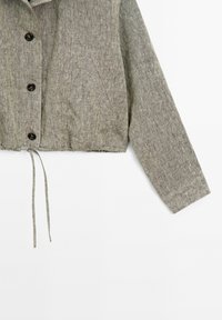 Giacca cropped in lino grigio con chiusura a bottoni, taschino sul petto e orlo con coulisse. Presenta maniche lunghe e un tessuto testurizzato.