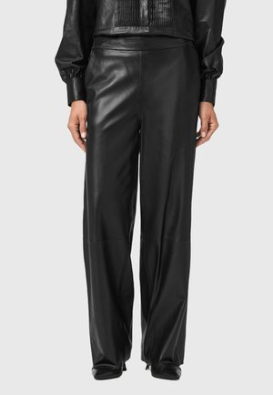 Pantaloni in pelle nera con fit morbido, caratterizzati da gambe ampie e una texture liscia. Cuciture evidenti che corrono verticalmente lungo la parte frontale.