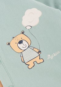 Light blue fabric features a cartoon bear with a striped shirt, holding a balloon. Notable details include the bear's rounded shape and facial expression.