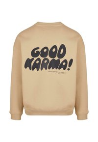 Béžová mikina s okrúhlym výstrihom a rebrovanými manžetami, na chrbte s veľkým čiernym textom "DOBRÁ KARMA!".