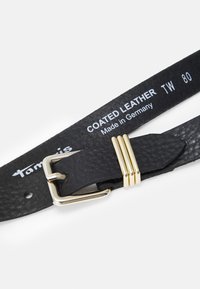 Ceinture en cuir noir enduit, dotée d'une boucle en métal doré et de trois anneaux dorés en accent. Étiquette de la marque visible sur la lanière.