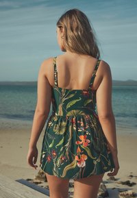 Rochie verde cu flori, cu bretele subtiri, cu modele vibrante de plante tropicale și flori. Croiala este lejeră, cu fustă evazată.