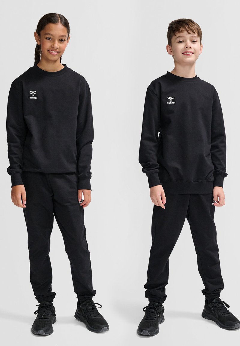 Set di felpa nera e pantaloni realizzato in tessuto morbido. Presenta un logo sul petto e polsini elastici sui pantaloni. Entrambi gli abbigliamenti sono semplici e coerenti.