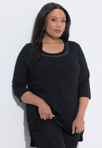 Black three-quarter sleeve tunic top featuring a scoop neckline adorned with small metal studs. Smooth fabric with a loose fit.