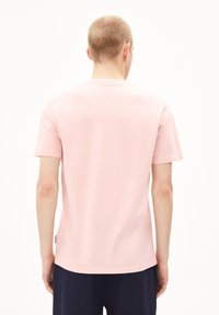 Lichtroze t-shirt met korte mouwen, gemaakt van katoen, met een ronde hals en een rechte snit. Bevat een klein merklabel aan de zijkant.