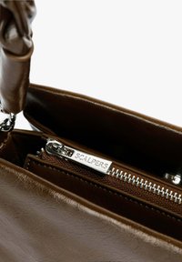 Bolso de mano de cuero marrón con un bolsillo interior con cremallera. Presenta un tirador de cremallera plateado y una textura suave. Asa resistente para llevar.