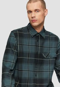 Czarna i turkusowa koszula w krate, zapinana na guziki, z kołnierzykiem i jedną kieszenią na piersi. Gładki materiał o dopasowanym kroju.