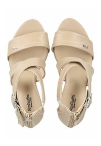 Sandali in pelle beige con più cinturini incrociati, punta arrotondata e fibbia alla caviglia. Presentano una soletta con logo stampato e dettagli in cucitura bianca.