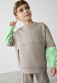 Grauer Sweatshirt mit mintgrünen Ärmeln, mit der Aufschrift "AKER" in hellgrüner Schrift und seitlicher Reißverschlusstasche. Weiches Baumwollmischgewebe.