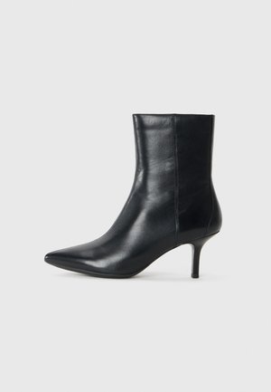 Stivale alla caviglia in pelle nera con punta appuntita, tacco sottile, texture liscia e dettagli di cucitura minimi. Design classico adatto a diversi outfit.