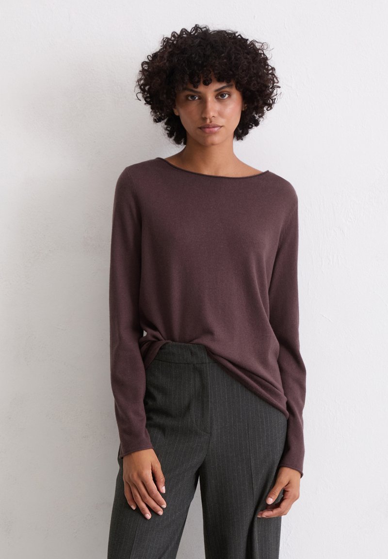 Sarkanais burgundijas garām piedurknēm, brīva silueta, ar plašu noapaļotu kakla izgriezumu, kopā ar pelēkām svītrainām biksēm. Redzama rakstaina virsma.