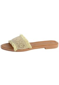 Open-toe sandaal in lichtgele geweven stof met een franjestrik. Bruine platte zool, minimaal gestikt en geometrisch patroon op de strik.