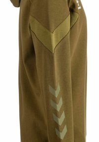 Oliwkowy pulower o fakturowanej tkaninie, z akcentami na ramionach w kształcie zygzaków oraz skośnymi wzorami w jaśniejszym odcieniu na rękawie.