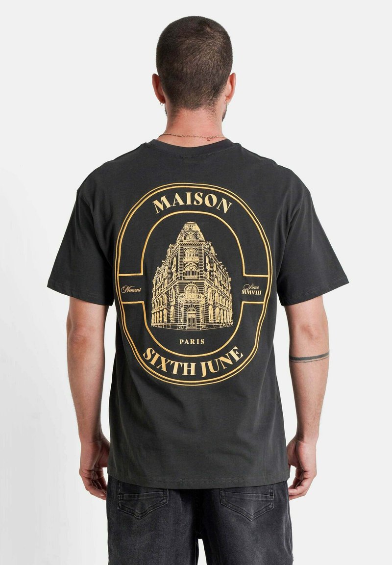 Zwarte katoenen t-shirt met een grote gouden afbeelding van een gebouw en de tekst "MAISON PARIS SIXTH JUNE" in een cirkel op de achterkant. Casual pasvorm.