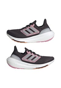 Svarta sportskor med en texturerad övre del i tyg, rosa detaljer, tre silverstrimmor och en tjock vit mellansula med en rosa och beige yttersula.