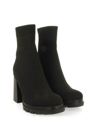 Botas negras hasta el tobillo con parte superior de punto, tacón alto de bloque, suela gruesa y puño acanalado. Tela texturizada con acabado suave.