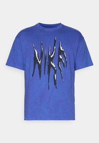 Camiseta de algodón azul con cuello redondo, que presenta un diseño gráfico en blanco y negro en la parte frontal que se asemeja a letras estilizadas.