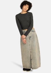 Musta lyhythihainen crop-top, joka on yhdistetty vaaleansiniseen farkkupitkään hameeseen, jossa on etupilkku ja yksinkertaisia ompelutietoja.