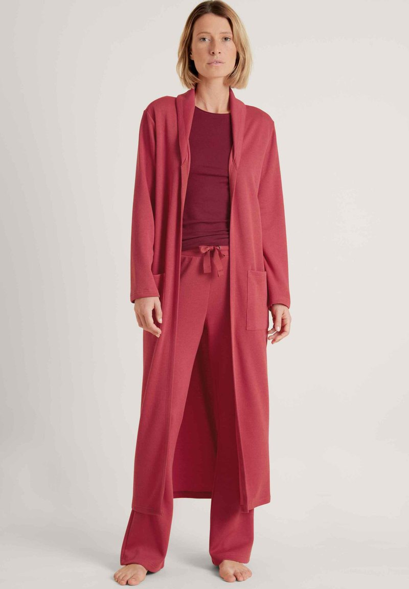 Rotes Lounge-Set bestehend aus einem langen, offenen Cardigan mit Taschen und passenden Jogginghosen mit Kordelzug. Weicher Stoff mit glatter Textur.