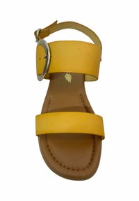 Sándal de cuero amarillo con dos correas anchas, una hebilla de metal circular y una suela texturizada marrón. Acabado suave y diseño plano.
