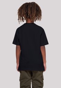 Sort kortærmet t-shirt med rund halsudskæring, glat stof og afslappet pasform, båret med cargo bukser, set fra ryggen.
