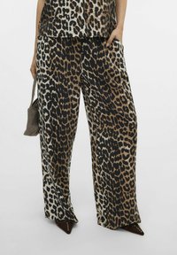 Pantalons à jambes larges en imprimé léopard dans un tissu doux, présentant des nuances de marron et noir avec une texture lisse et des poches latérales.