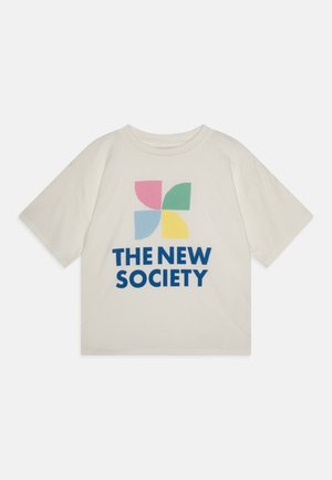 Camiseta color crema hecha de algodón, con un diseño gráfico colorido de formas superpuestas en rosa, azul, verde y amarillo, con texto en negrita.
