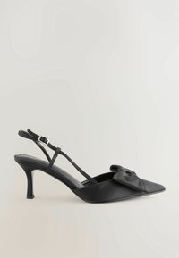 Chaussure noire à talon haut avec bride arrière, bout pointu et nœud décoratif sur le côté, dotée d'une fine bride de cheville et d'un talon kitten.