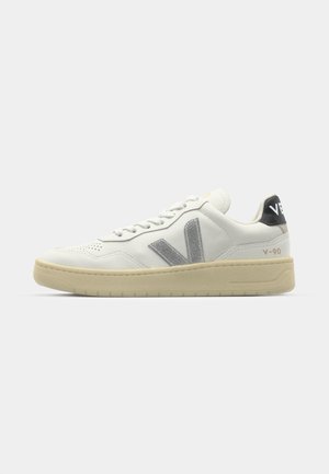 White leather sneaker with silver logo and accents. Features round toe, flat laces, and a beige rubber sole. Black heel tab labeled "V-90."