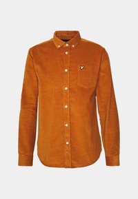 Camisa de pana en un color naranja quemado con cuello tipo button-down, mangas largas, bolsillo en el pecho y un pequeño logo amarillo en el bolsillo.