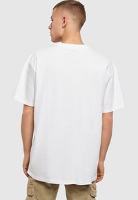 Hvid bomulds T-shirt med afslappet pasform, rund halsudskæring og korte ærmer, med en ensfarvet ryg og ingen synlige logoer eller mønstre.