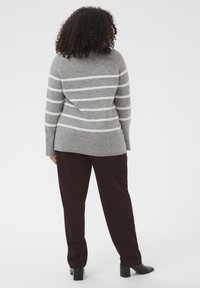Pull rayé gris avec des rayures blanches ; silhouette ajustée, ourlet côtelé. Assorti avec un pantalon bordeaux foncé et des chaussures à talons noires.