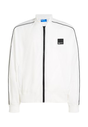 Veste bomber blanche avec fermeture éclair avant, bandes latérales noires, poignets élastiques et petit patch logo noir sur la poitrine gauche.