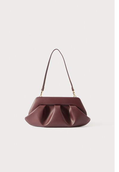Sac à main en cuir bordeaux doux avec des plis structurés et une seule bandoulière maintenue par des fermoirs dorés sur un fond blanc uni.